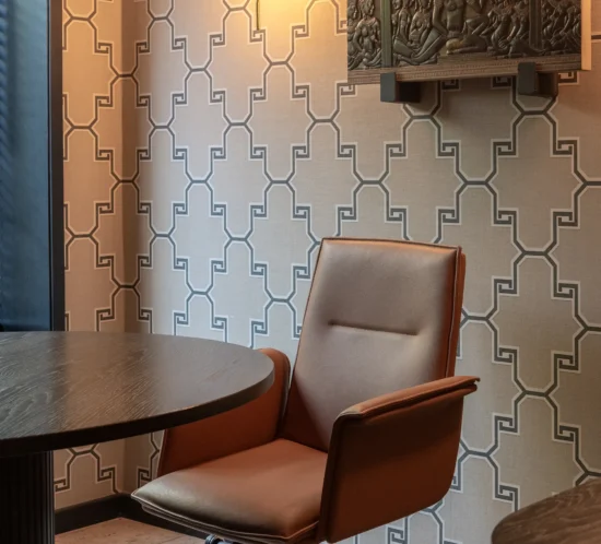 Oficina contemporánea con materiales nobles, papeles murales texturizados, mobiliario de madera y cuero, y una atmósfera elegante inspirada en referencias orientales reinterpretadas desde una estética sobria y sofisticada.