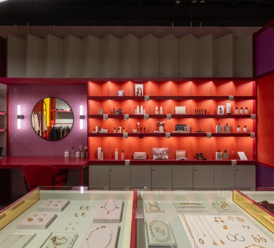 Interior de Oz con mobiliario geométrico, paleta amarilla y roja, exhibición multimarca y elementos inspirados en galerías contemporáneas que promueven una experiencia de descubrimiento y exploración.